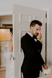 bride and groom talk behind door