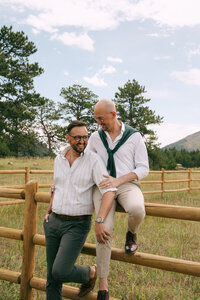 LGBTQ+ couple sitting on the fence looking at each other