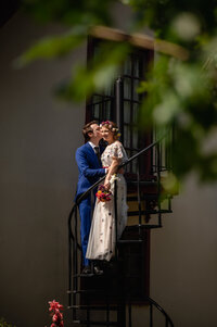 A couple kiss on an outdoor staircase at the grove