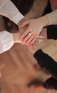People stack their hands together in unity