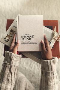 Close-up of the Self Love Tonic journal being held in a woman's hands.
