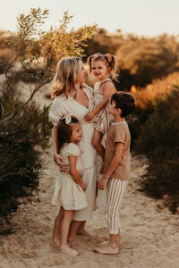 Mother with her children dressed in neutral tones during a boho-inspired outdoor family session in Orange County