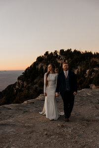 bride and groom holding hands on top of mountain