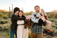 Family snuggling newborn on the couch. Captured by Cactus & Pine Photography