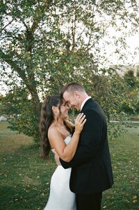 Bride and groom kissing among greenery taken by east coast wedding photographers