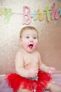 February cake smash session with rose gold colors and baby with cake all over her