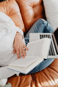 Woman flipping through book with computer