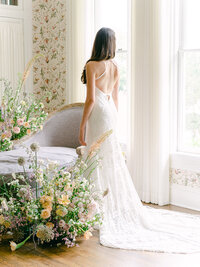 Bride looking out the window  of the bridal suite at Woodbine Mansion  in  Round Rock, Texas