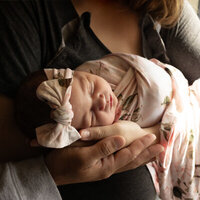 Newborn baby being held in mom and dads hands.
