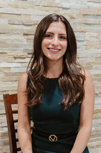 Kristy Clarke, owner of The Wild Collective standing in front of a graffiti wall in a navy blue dress, smiling at the camera.