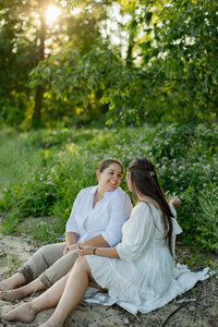Two people stand closely, adorned in cozy plaid and knitted sweaters. A large, sparkling ring catches the eye on one's hand as they embrace warmly. Captured with the finesse of a New England photographer, this moment exudes fine art elegance and documentary-style intimacy.