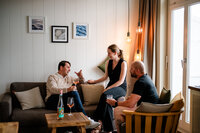 Drei Menschen sitzen im Wohnbereich eines Apartments und trinken Wein.