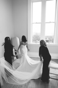 Mom and sister helping bride with her dress