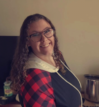 Woman with curly hair and glasses smiling
