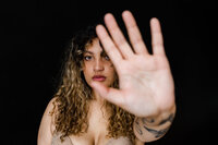 Curly haired lady sticking her hand out by Charlotte boudoir photographer, Steph