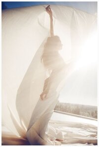 Woman standing in front of the sun with light shining through sheer fabric