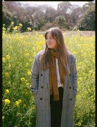 woman standing in front of field of yellow flowers 
