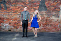 couple poses for engagement portrait against brick background in downtown conway, south carolina