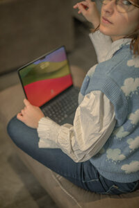 Francesca sitting on the couch with a macbook 