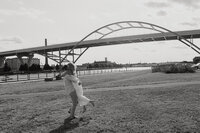A bride and groom having an embrace in front of an architectural bridge 