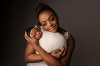 Mother holding her newborn baby wrapped in cream wrap photo taken by Detroit newborn photographer Kat Figlak