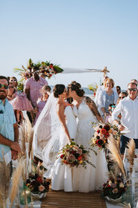 bride and  bride kissing  at the end of ceremony  on the beach