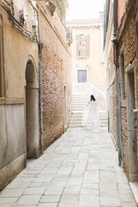 Bride runs down cobblestone street in Venice, Italy