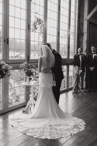 black and white photo of bride and groom from behind at their church wedding ceremony