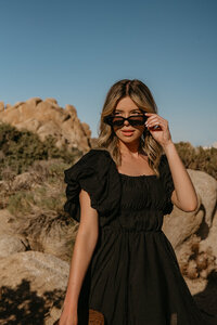 girl in dessert wearing black puffy dress and sunglasses