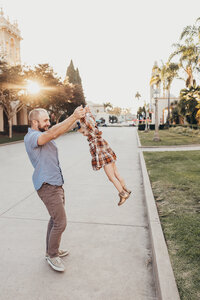 A father picks up his young daughter while they play in Balboa Park