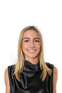 Blonde woman in a black top, smiling at the camera while posing for a professional headshot in Westchester, NY.