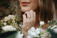 Bride showing off her wedding ring while standing in the autumn air and holding her florals