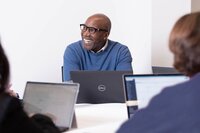 Black CEO in a meeting smiling over his laptop