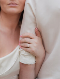engagement session. close up shot of women with hand around mans arm showing her engagement ring.