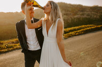bride and groom drinking champagne from the bottle
