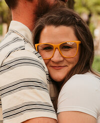 woman nestled into partners chest smiling at the camera