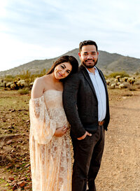Gorgeous expecting couple in dress clothing hugging while mom holds baby bump