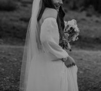 Bride holds her dress as she hikes through the mountains