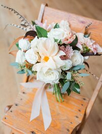 Bohemian bridal bouquet with feathers sitting in a chair