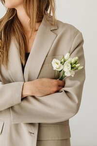 Woman in a beige suit holding a flower