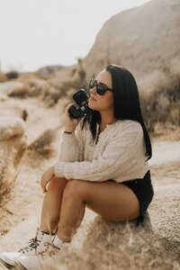 Sophia Savage sitting in desert with camera