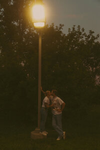 An engaged couple holds one another's faces close and giggle during an intimate moment in the sunset