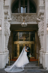 Bride and groom standing outside of a building holding each other close