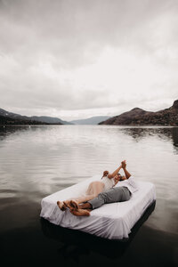 Couple lay out on a floating mattress on the lake