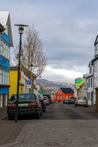 A bride and groom stand at an overlook looking out enjoying the views. Their backs are facing the camera with the grooms arm wrapped around the bride. The bride is wearing a lace white wedding gown with a train and the groom is in an olive green suit. There are rock and tree covered mountains in the distance with the sky turning pink from the sunset.