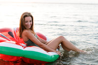 Picture of Nicole Marie Photography floating on a watermelon float in Ocean City New Jersey. She is wearing a dark green bathing suit from Aerie.