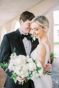 Bride and groom embrace on their wedding day holding bouquet at The Parador