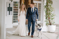 bride and groom walking with their dog of honor beside them