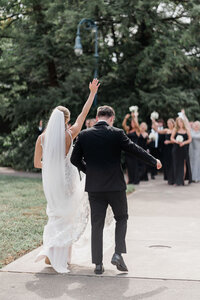 bride and groom walking towards their bridal party celebrating