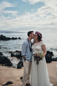 Husband gives his new wife a kiss on the cheek in Hawaii